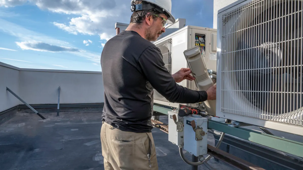 A technician works on a commercial HVAC unit. As systems age, technology that can monitor small performance changes can help facilities managers spot problems before they become costly to repair, an industry executive says.